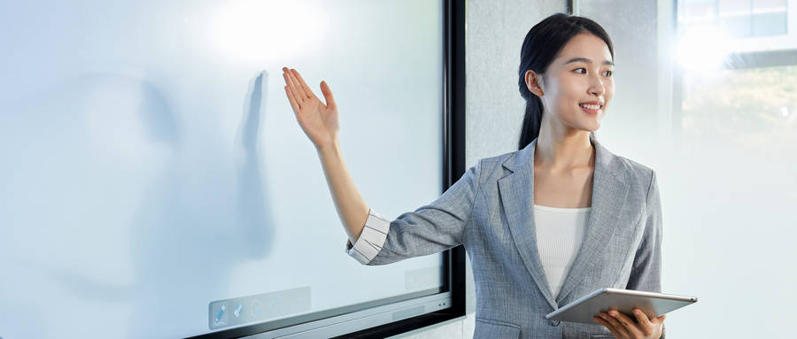 一位穿著西裝的女士指著白板，用手勢提高她的說服性演講技巧。