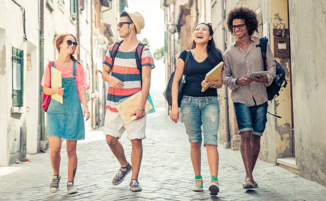 一群年輕人漫步在鵝卵石街道上，展示學習新語言的樂趣。
